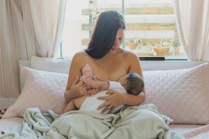 Une mère qui allaite son bébé assise dans son lit